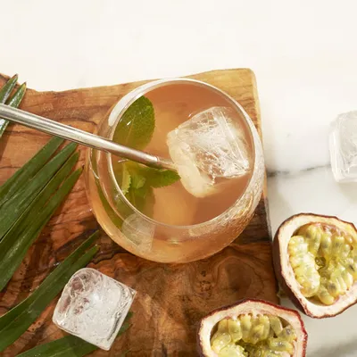 Primo piano di cocktail con passion fruit e lime, servito in un bicchiere o in una coppa con ingredienti decorativi e luce morbida.