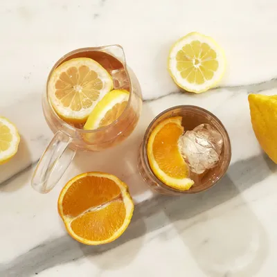 Primo piano di cocktail agrumato con fettine d'arancia, servito in un bicchiere o in una coppa con ingredienti decorativi e luce morbida.