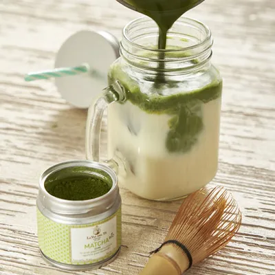 Crema o latte al matcha viene versato in un barattolo di vetro, creando una colata verde densa e ben visibile.