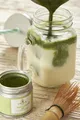 Crema o latte al matcha viene versato in un barattolo di vetro, creando una colata verde densa e ben visibile.