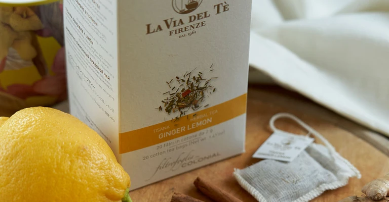 Immagine di scatola bianca di tè con limoni e zenzero, fotografata come prodotto in un set curato con fondo, ingredienti o elementi decorativi coerenti.