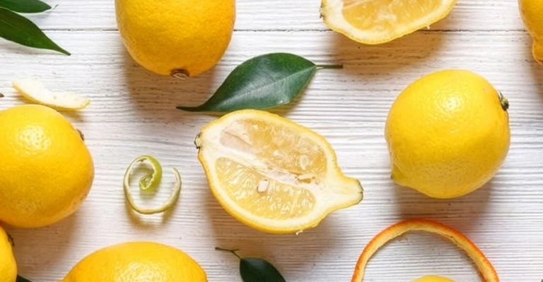 Composizione con limoni interi e tagliati disposti su uno sfondo chiaro, in una fotografia luminosa e pulita.